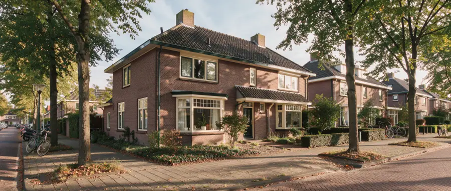 Vooroorlogse bakstenen woning in een groene straat, met dak en ramen duidelijk in beeld